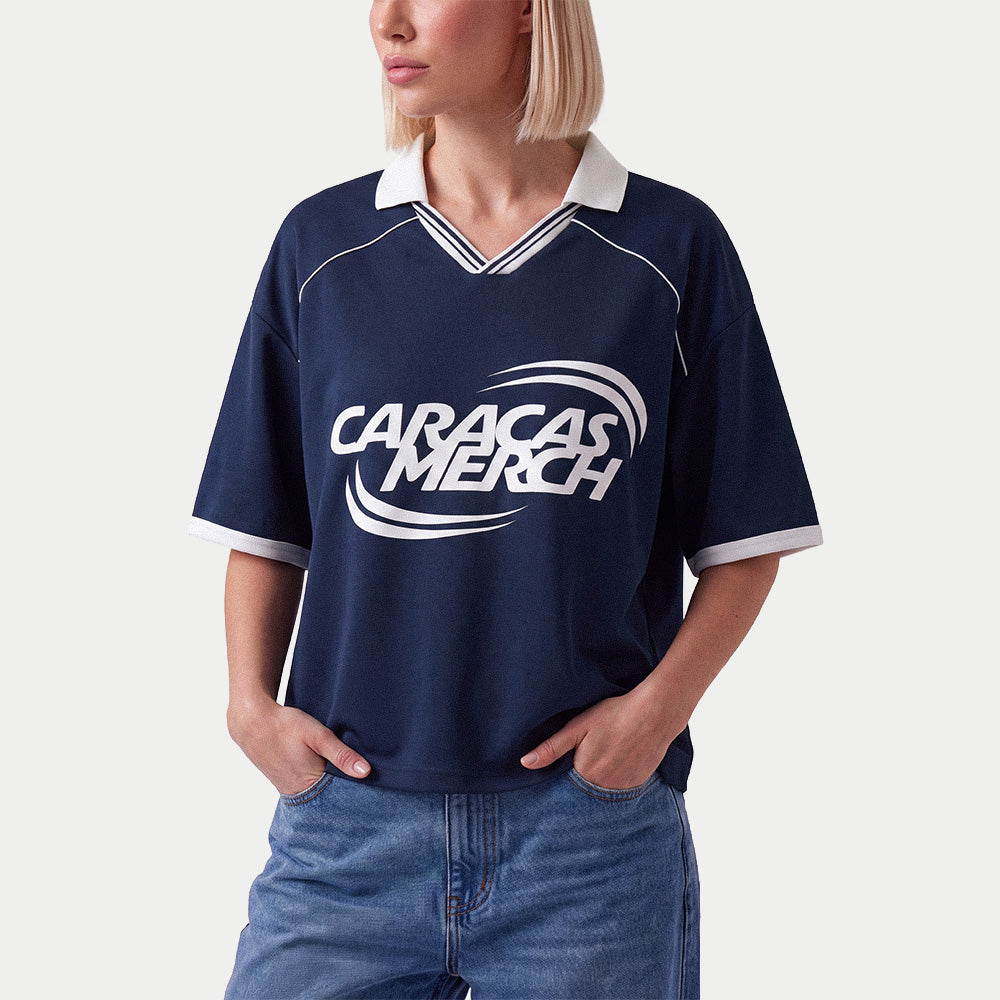 Mujer llevando la camiseta de fútbol boxy azul marino de Caracas Merch con vaqueros